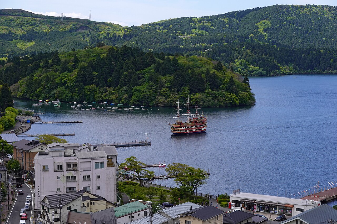 Statek piracki Hakone Sightseeing Cruise płynący po jeziorze Ashi obok zabudowy i pomostów Motohakone, maj 2026.